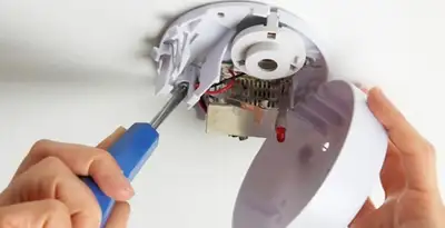 Certified technician wiring smoke detector during installation in Pasadena, CA